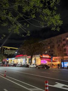 a city street with cars parked in front of buildings at Центр города Цум in Almaty