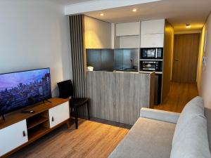 ein Wohnzimmer mit Couch und Fernseher und eine Küche in der Unterkunft A Pasos Tres Cruces in Montevideo