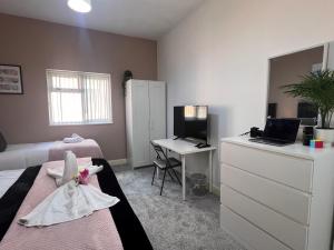 Un dormitorio con una cama y un escritorio con una computadora. en Syster Properties Comfortable Leicester Glen Cottage Stay with Free Parking LE3, en Leicester