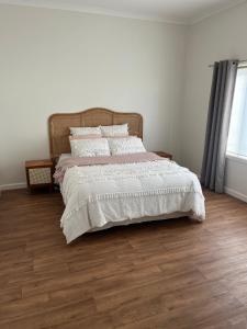 a bedroom with a bed with white sheets and wooden floors at Ocean Road Retreat in Peterborough +5 photos