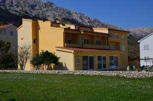 a large yellow house with a stone wall at Bed & Breakfast Dani in Baška