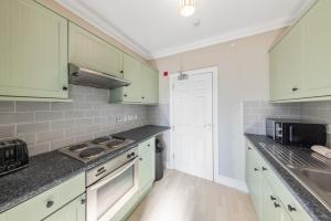a kitchen with white cabinets and gray counter tops at Modern King Bed WiFi Kitchen Perfect for Long Stay in Gravesend