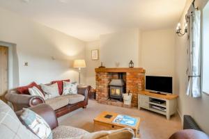 ein Wohnzimmer mit Couch und Kamin in der Unterkunft Carrstone Cottage in Grimston