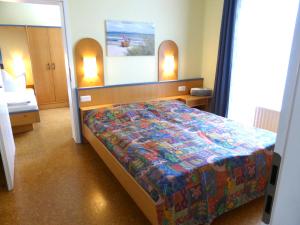 a bedroom with a bed with a colorful comforter at Strandläufer im Haus Strelasund in Binz