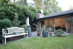 a white bench in a yard next to a house at Schöner Bungalow Am Venekotensee in Elmpt +8 photos