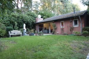 a red brick house with a bench in the yard at Schöner Bungalow Am Venekotensee in Elmpt