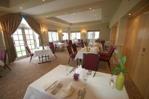 a dining room with white tables and chairs at Kings Court Hotel in Alcester