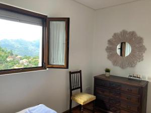 a bedroom with a dresser and a mirror and a chair at Casa Da Laija in Cova +8 photos