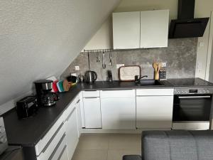 a kitchen with white cabinets and a black counter top at Ferienwohnung Linus OG 95172 in Rhauderfehn