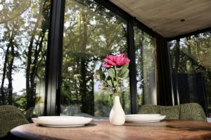 a pink rose in a white vase on a table at Caravanserei Resort Oberhavel in Oranienburg