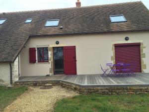a house with a wooden deck with purple chairs on it at Gîte les petits cris 