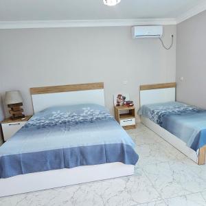 - une chambre avec 2 lits avec des draps bleus dans l'établissement Eliska, à Gonio