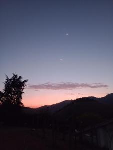 a sunset with a tree and mountains in the background at Recanto das Videiras in Maria da Fé +165 photos