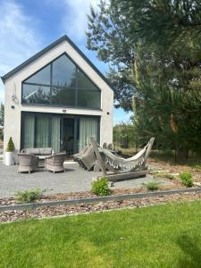 a house with a hammock in front of it at DOMKI Nad Jeziorami Niedźwiady in Ślesin +3 photos