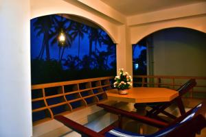 a table and chairs on a balcony at night at Marari Edens in Mararikulam