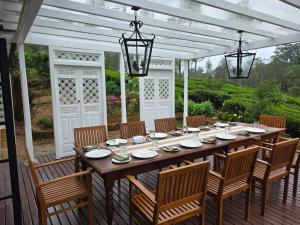 einen großen Holztisch auf einer Terrasse mit Stühlen in der Unterkunft Powysland Bungalow in Nuwara Eliya