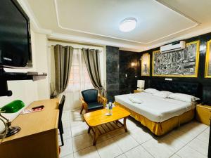 a bedroom with a bed and a desk and a tv at Hôtel du Boulevard in Brazzaville