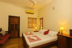 a bedroom with a bed with white sheets and red pillows at Haris Farm House in Kannur