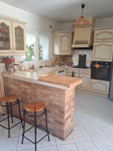 a kitchen with a brick counter and two stools at Chez Loti in Louviers