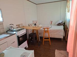 una piccola cucina con fornelli, un tavolo e un letto di Monoambiente contenedor "Sele's" a Punta Colorada Altre 11 foto