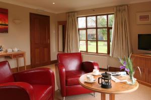 a living room with red chairs and a table and a television at Ivy House Country Hotel in Lowestoft