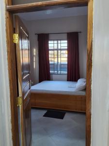 a small bedroom with a bed and a window at Adriel House in Dodoma +5 photos