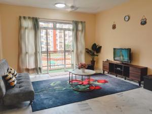 a living room with a couch and a tv and a table at Iris 2 Bedroom Pool View Balcony in Kampong Tanah Merah