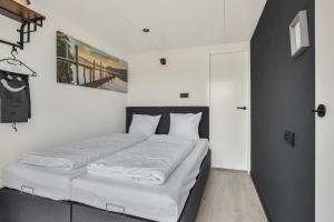 a bedroom with a large bed with white sheets at Houseboat Mookerplas met Hottub in Middelaar