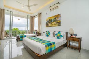 a bedroom with two beds and a balcony at The Cloud Hanthana, Kandy in Kandy