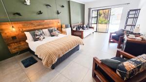 a bedroom with a bed and a couch and a chair at Villa-né Guesthouse in Potchefstroom