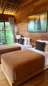 drie bedden in een kamer met houten wanden bij Kaju Villa Canggu in Canggu