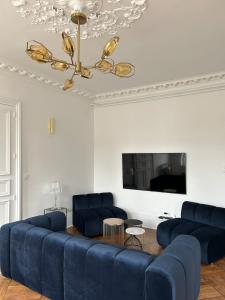a living room with a blue couch and a tv at Gîte Vosges en Ville luxueux appartement Duplex avec sauna espace bien être au centre d'Epinal in Épinal
