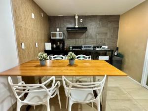 a kitchen with a wooden table and white chairs at CASA NAMI- Cancún Beachside Suites in Cancún