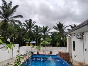 a swimming pool in front of a house with palm trees at Unit 01 Homestay Private pool & Netflix Muar in Sungai Mati