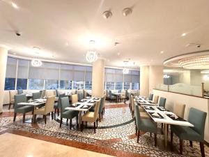 a dining room with tables and chairs and windows at Grand Continental Hotel in Abu Dhabi