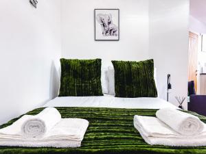 プジーにあるChic Studio, Free parking, Sleeps 2のベッドルーム1室(緑と白のベッド、タオル付)