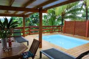 a swimming pool on a deck with a pergola at Villa Barthelemy - Gite 2 in Goyave