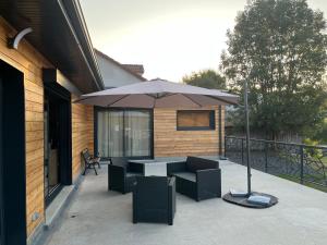 a patio with an umbrella and a table and chairs at Charmant logement avec terrasse et parking sécurisé in Arpajon-sur-Cère