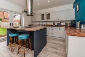 BalbyにあるThe Yorkshire House, 3-Bed, Parking & Netflixの白いキャビネットと青い壁の広いキッチン