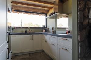 a kitchen with white cabinets and a large window at Landgoed Boneman in Meddoo +6 photos