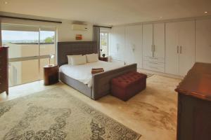 a bedroom with a bed and a couch and a window at Casa De Palmera Langebaan in Langebaan