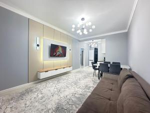 a living room with a couch and a dining room at Двухкомнатная квартира с евроремонтом в центре Алматы, рядом с ТРЦ MEGA Center in Almaty