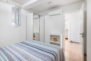 a white bedroom with a bed and a mirror at Paraná in Quarteira