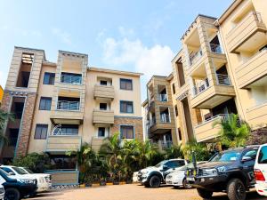 a row of apartment buildings with cars parked in a parking lot at 3-bedroom Spacious Munyonyo Home in Kampala