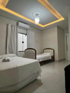 a bedroom with two beds and a large window at Casa aconchegante 2min do centro in Primavera do Leste