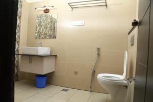 a bathroom with a toilet and a sink at Hotel Orchard Coorg in Virajpet