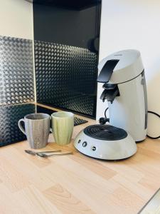 a coffee maker and two cups on a counter at Charmante maison avec terrasse in Saint-Omer-Capelle