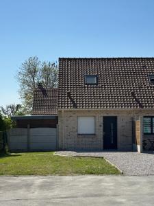 a brick house with a garage and a brown roof at Charmante maison avec terrasse in Saint-Omer-Capelle