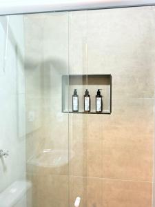 a bathroom with a shower with three bottles on a shelf at Pousada Casa Cerrado in Colinas Do Sul