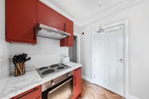 eine Küche mit roten Schränken und einem Herd in der Unterkunft Long Stay Ready King Bed Kitchen WiFi Town in Gravesend